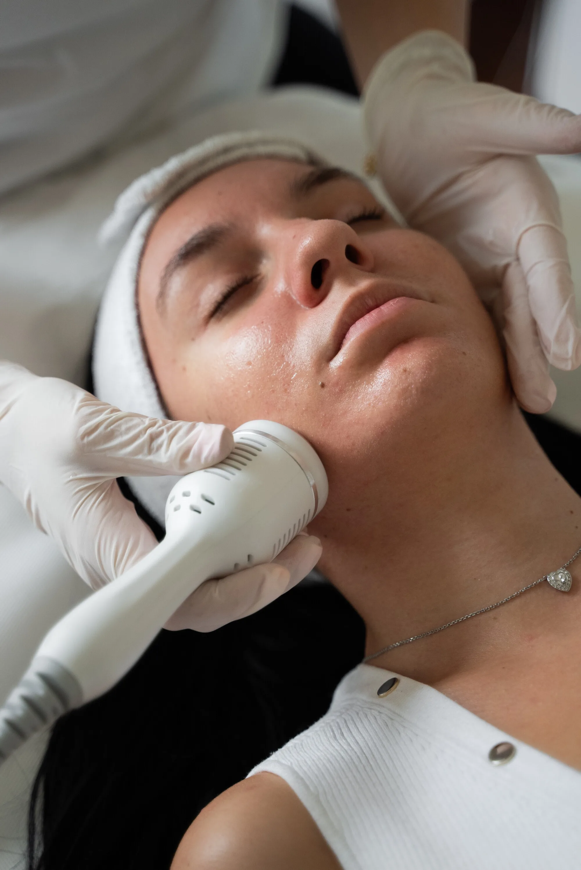Tretman Hydrafacial7u1: nastavak uređaja na obrazu, ruka terapeutkinje pridržava lice